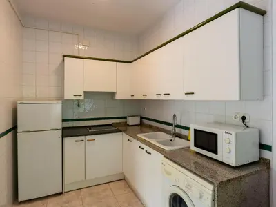 a kitchen with white cabinets and a sink and a microwave at Apartamentos Sunway Tara in Sitges