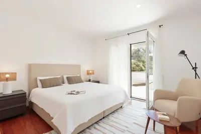 a bedroom with a white bed and a black chair at Luxury Seaview Villa by Olala Homes in Teià
