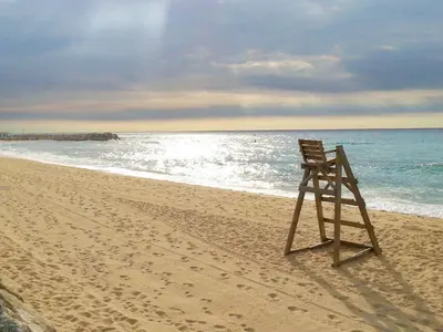 a chair sitting on the beach near the ocean at Complex Vicor in Vilassar de Mar