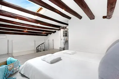 a bedroom with a white bed and wooden ceilings at Gracia 1872 in Barcelona