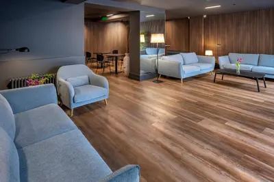 a waiting room with blue couches and chairs and wooden floors at Hostal Operaramblas in Barcelona