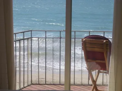 a chair sitting on a balcony looking at the beach at Sitges Beach Panorama in Sitges