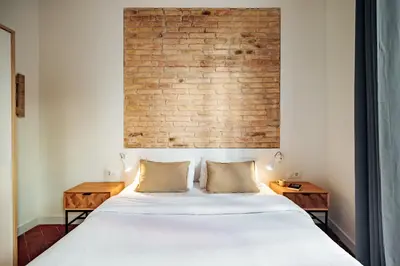 a bedroom with a white bed with a brick wall at Design Apartments by Olala Homes in Hospitalet de Llobregat