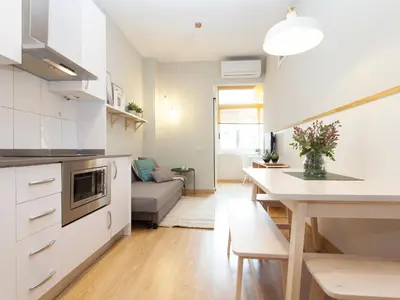 a kitchen and living room with a table and a couch at Cozy Gracia 2 bedrooms in Barcelona