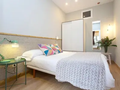 a bedroom with a large bed and a table at Cozy Gracia 2 bedrooms in Barcelona
