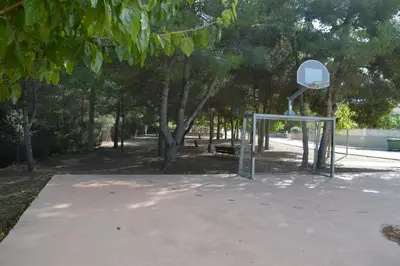 a basketball hoop in a park with trees at Vista Cunit in Cubelles