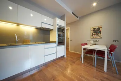 a kitchen with white cabinets and a table with red chairs at Bonavista Apartments - Passeig de Gracia in Barcelona