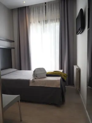 a bedroom with a bed and a window with curtains at Hostal Benidorm in Barcelona