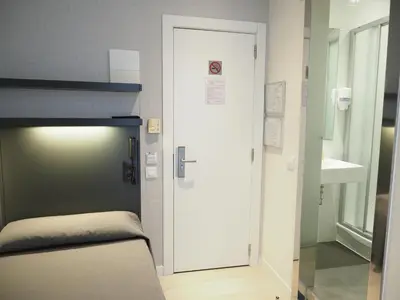 a room with a bed and a door with a sink at Hostal Benidorm in Barcelona