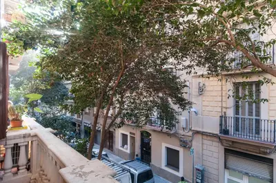 an apartment balcony with a tree in front of a building at Sarriá - Sant Gervasi in Barcelona