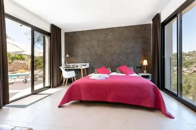 a bedroom with a large bed and large windows at Luxury Sitges Hills Villa in Olivella