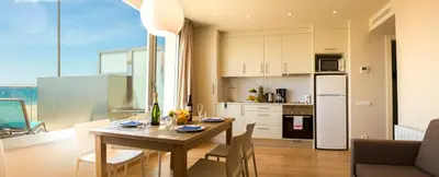 a kitchen and dining room with a table and chairs at Apartamentos Voramar in Castelldefels