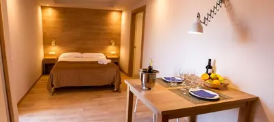 a room with a bed and a table with wine bottles at Apartamentos Voramar in Castelldefels