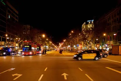 a city street at night with cars driving down the street at Habitat Apartments Bruc Terrace in Barcelona