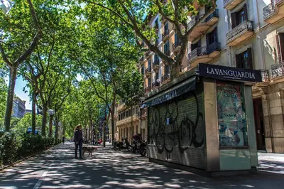 a woman walking a dog on a street with a building at Habitat Apartments Bruc Terrace in Barcelona