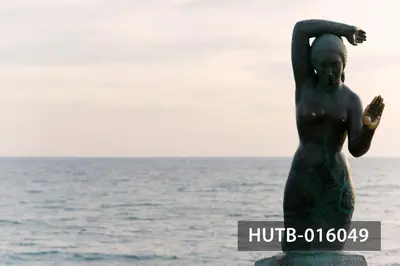a statue of a woman standing next to the ocean at Elegant Sitges Apartment in Sitges