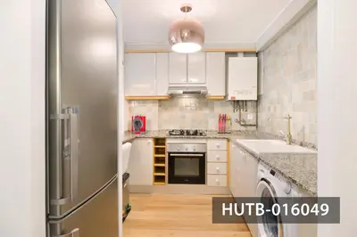 a kitchen with white cabinets and a stainless steel refrigerator at Elegant Sitges Apartment in Sitges