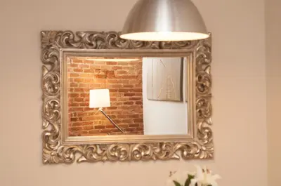 a mirror with a lamp in front of a brick wall at Charming Gracia 2 bedrooms in Barcelona