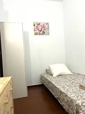 a small bedroom with a bed and a cabinet at Camp Nou Apartment WiFi in Barcelona