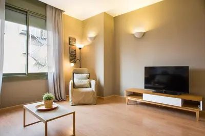 a living room with a flat screen tv and a chair at Bonavista Apartments - Pedrera in Barcelona