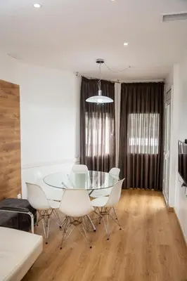 a dining room with a glass table and white chairs at DragonTree Barcelona - apartamentos turisticos 5 min from the BEACH in Barcelona
