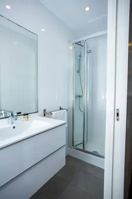 a white bathroom with a sink and a shower at DragonTree Barcelona - apartamentos turisticos 5 min from the BEACH in Barcelona