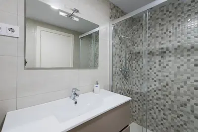 a white bathroom with a sink and a shower at Apartamento Manent in Premiá de Mar