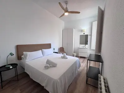 a bedroom with a white bed and a ceiling fan at Calma House Barcelona in Barcelona