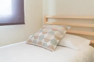a bed with a pillow on top of it at Contemporary Apartment Near Camp Nou and Fira Barcelona in Hospitalet de Llobregat