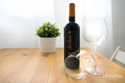 a bottle of wine and a glass on a wooden table at Hotelito Boutique Camp Nou in Hospitalet de Llobregat