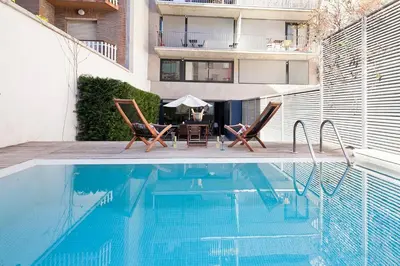 a swimming pool with two chairs and a table next to a building at Apartment Barcelona Rentals - Private Pool and Garden Center in Barcelona