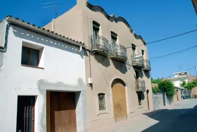 a white building with a wooden door on a street at Ca la Paula in Pla del Panadés