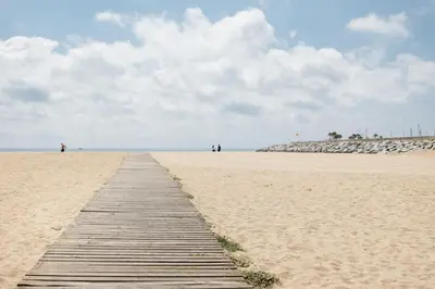 a wooden path on a sandy beach with people in the distance at Matarolux 7 in Mataró