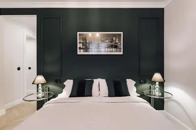 a bedroom with black walls and a white bed with two tables at Lunalux Apartment in Barcelona