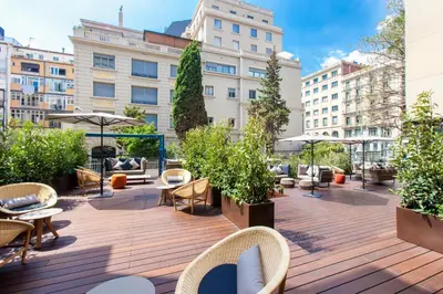 a rooftop deck with chairs and tables and buildings at Eurostars Barcelona Central in Barcelona