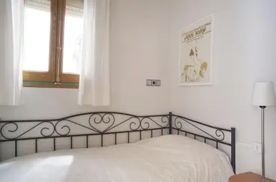 a bed in a white bedroom with a window at ApartEasy - Authentic Family Apartment in Barcelona