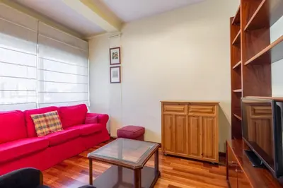 a living room with a red couch and a tv at ApartEasy - Port Barcelona in Barcelona