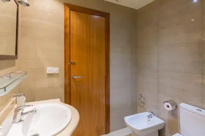 a bathroom with a sink and a toilet and a wooden door at ApartEasy - Family Apartment Sant Antoni in Barcelona