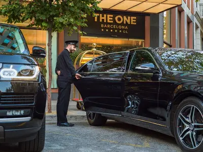 a man is standing next to a black car at The One Barcelona GL in Barcelona