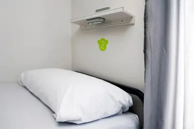 a bed with a white pillow next to a window at Meeting Point Hostels in Barcelona