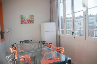 a dining room with a glass table and orange chairs at Feel at Sants Apartments in Barcelona