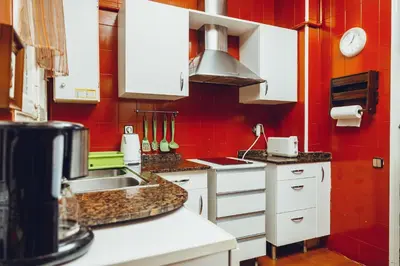 a kitchen with white cabinets and a red wall at Grand Central Apartment in Barcelona