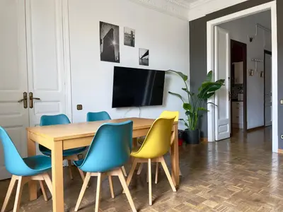 a dining room with a wooden table and blue and yellow chairs at Grand Central Apartment in Barcelona