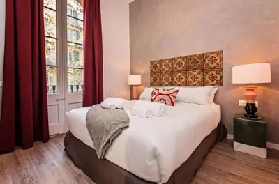 a bedroom with a large white bed with red curtains at Sweett - La Pedrera - Paseo de Gracia in Barcelona