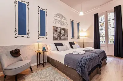 a bedroom with a bed and a chair and windows at Sweett - La Pedrera - Paseo de Gracia in Barcelona