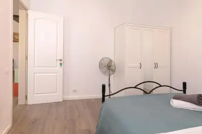 a white bedroom with a bed and a fan at Apartment Carrer de Joan in Barcelona