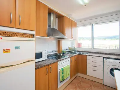 a kitchen with wooden cabinets and a large window at Apartment Mariola by Interhome in Sant Andreu de Llavaneres