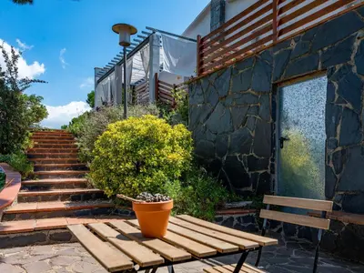 a wooden bench sitting next to a building with stairs at Holiday Home Ginesteres by Interhome in Argentona