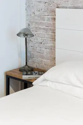 a bedroom with a bed and a table with a lamp at Lovely loft near Barcelona center in Barcelona