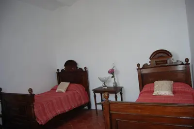 a bedroom with two beds with red sheets and a table at Can plana de baix in San Pol de Mar